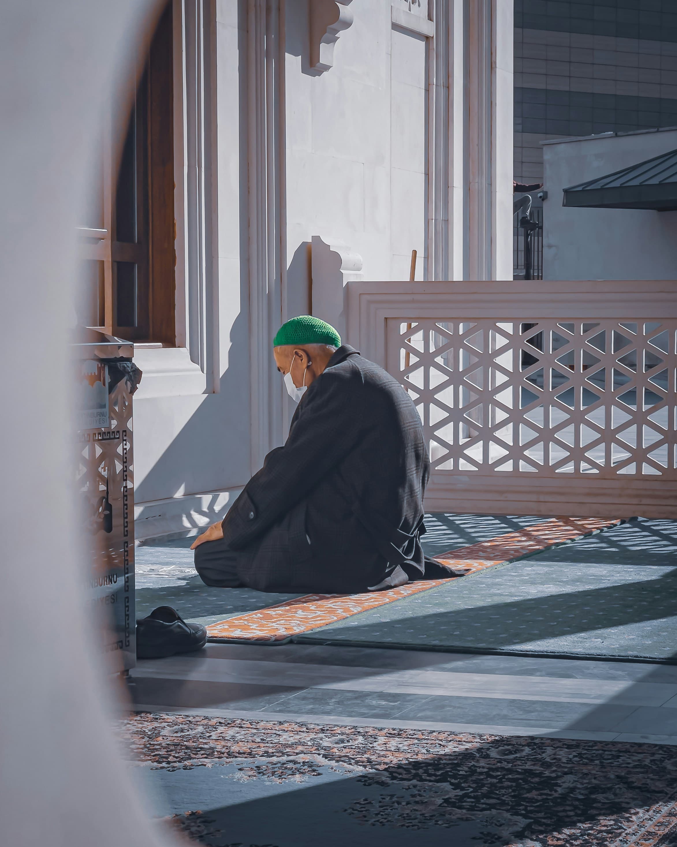 An older man praying beside a carved screen