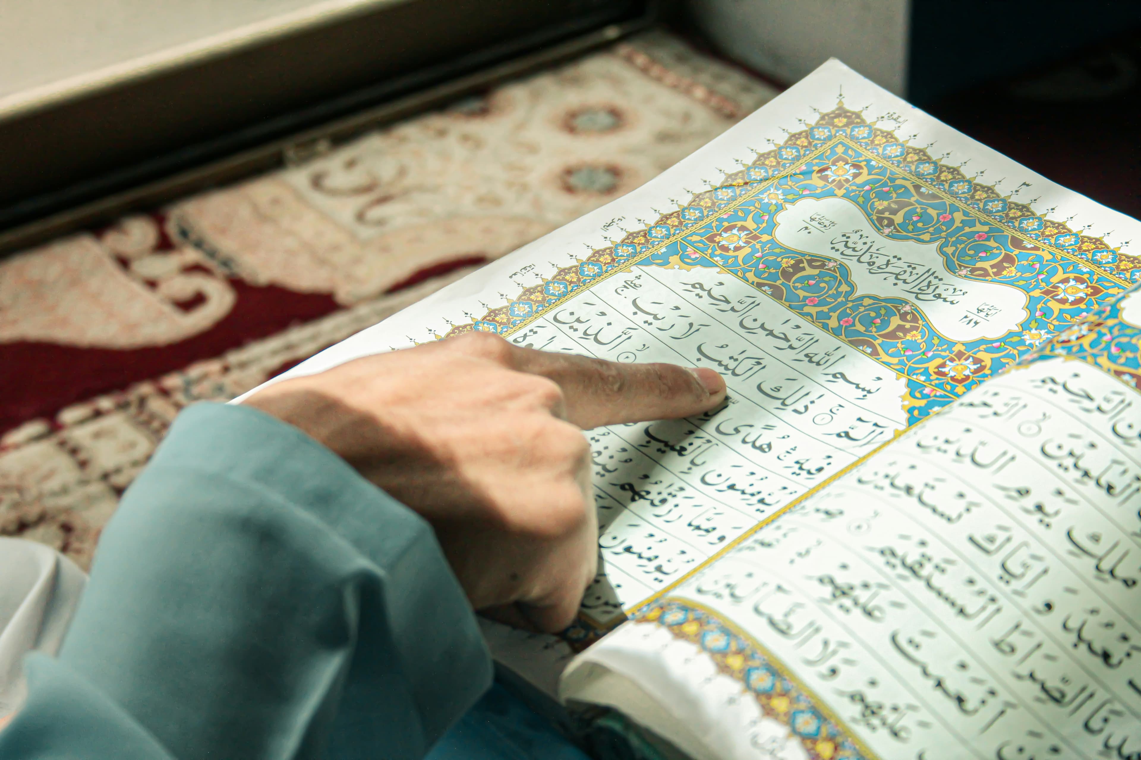 A finger following the words in an open Qur'an