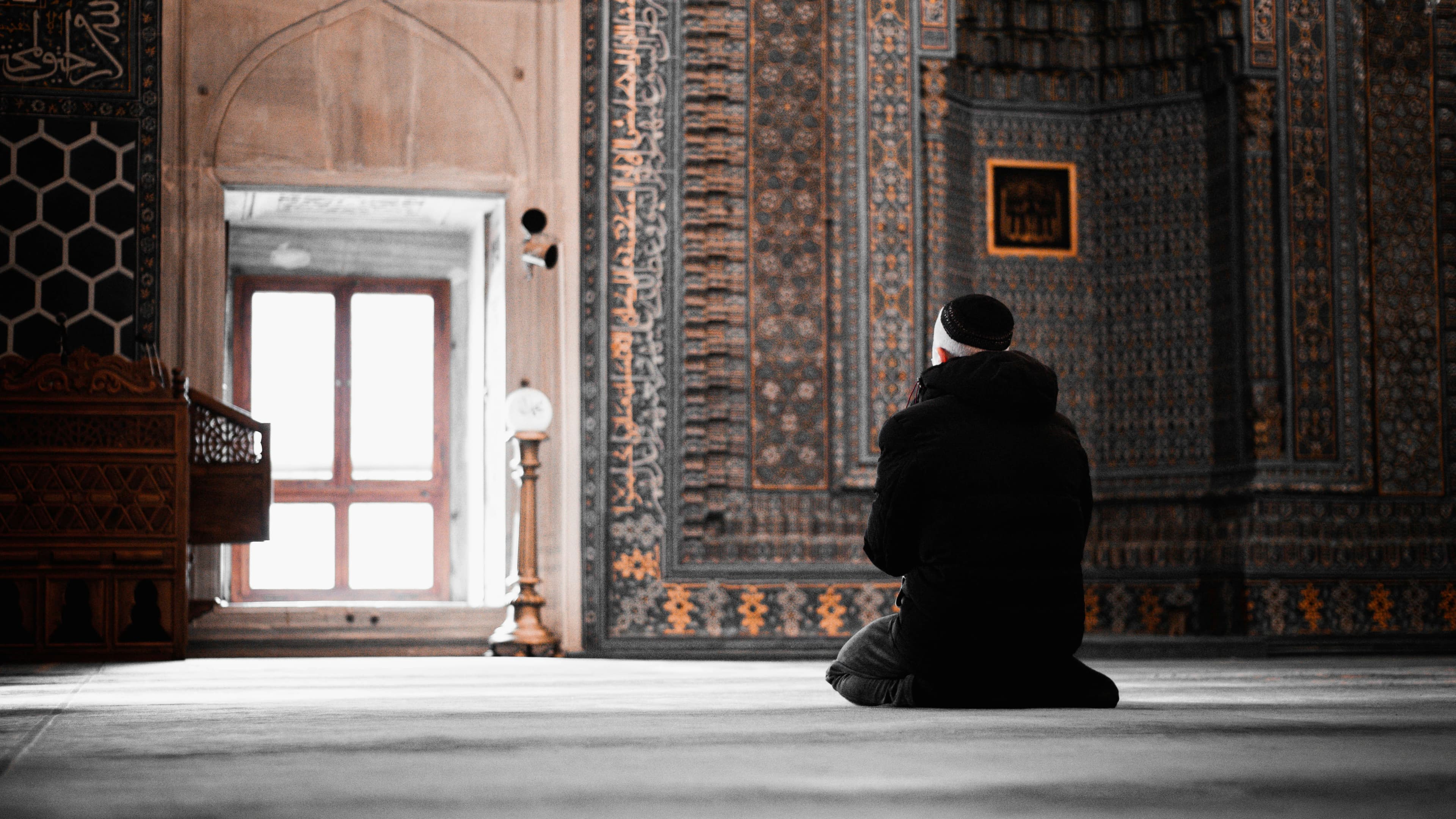 A man praying in front of the mihrab