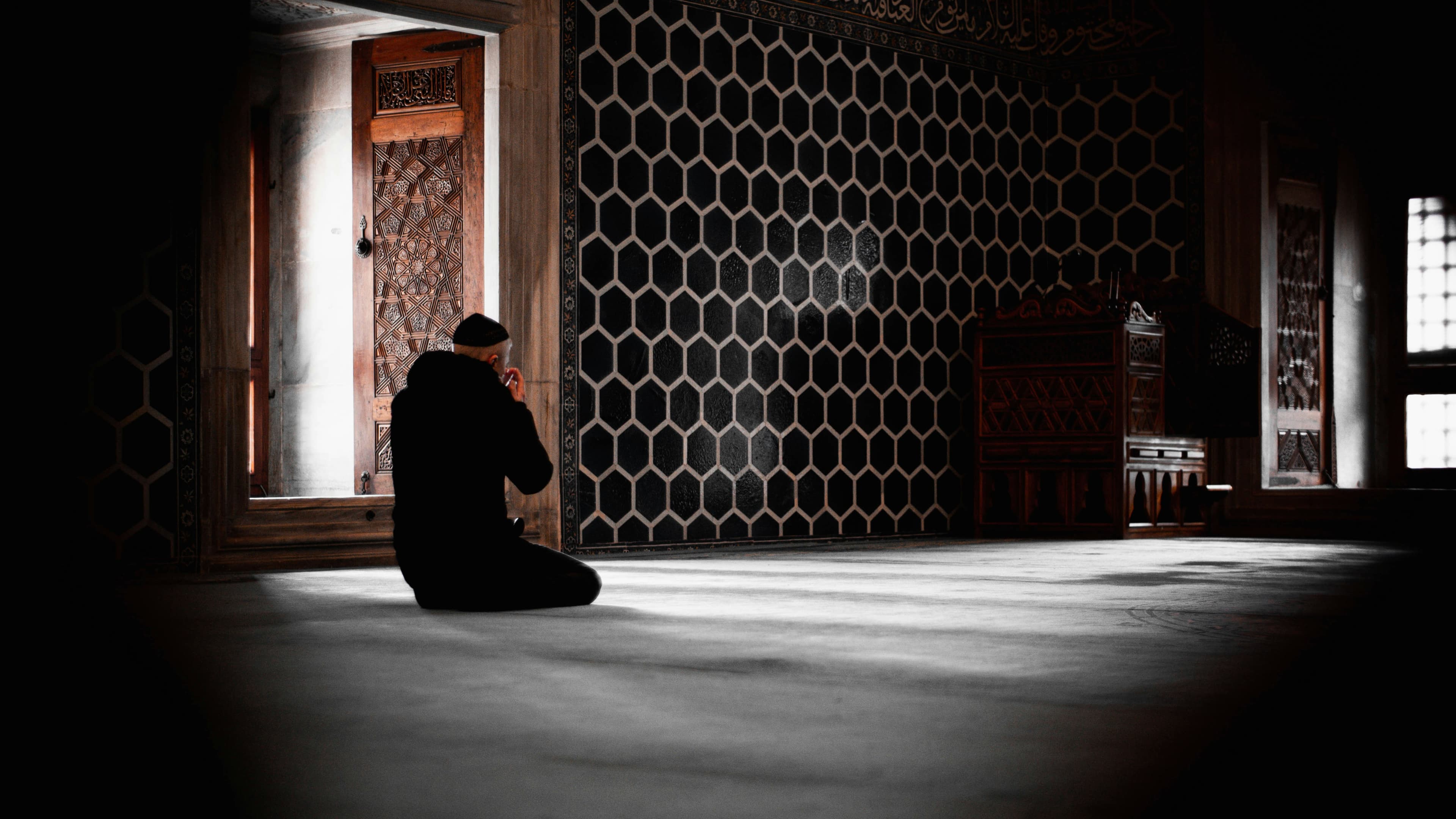 A man praying alone in a dark masjid