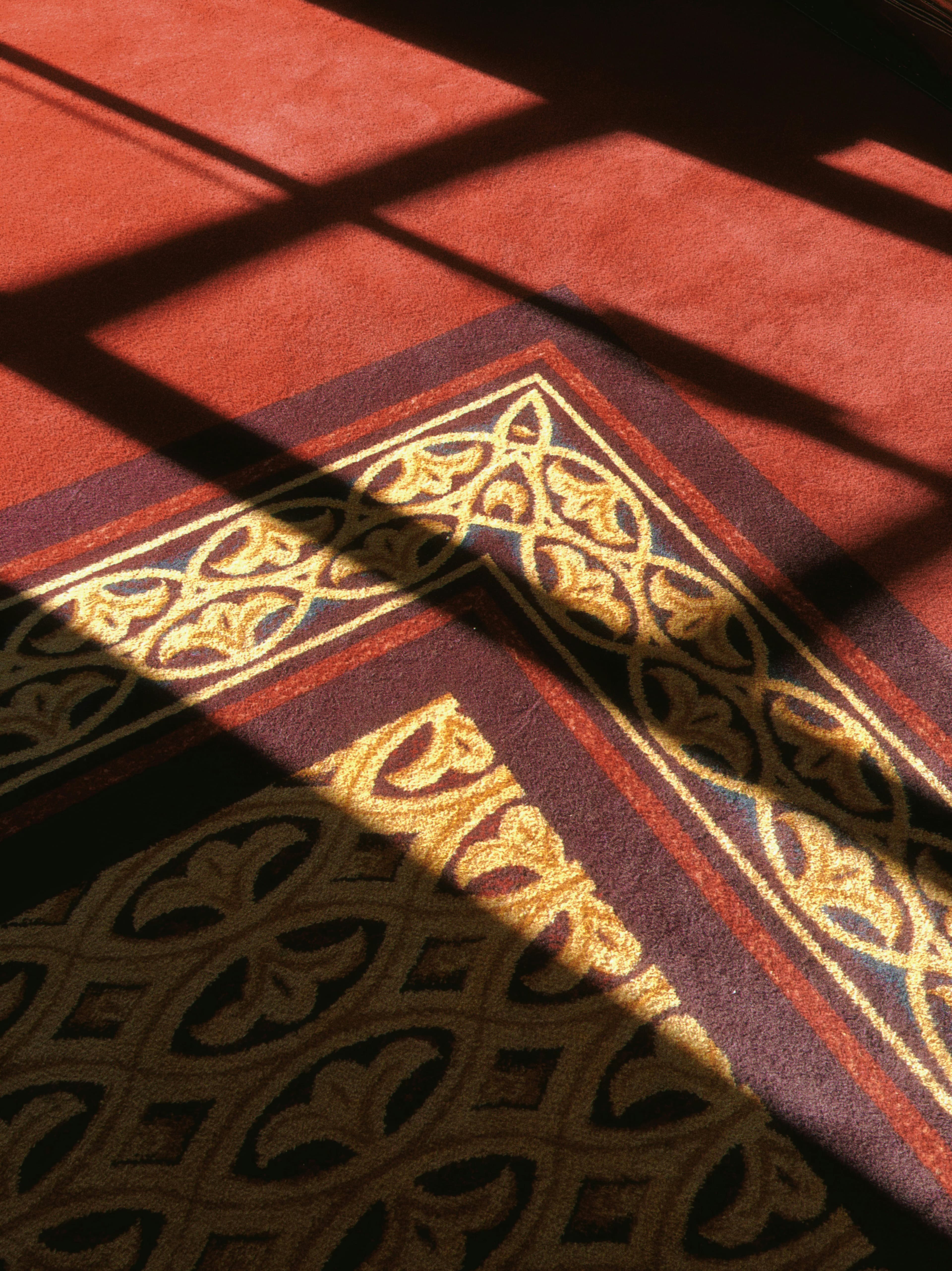 Sunlight across the pattern of a masjid carpet