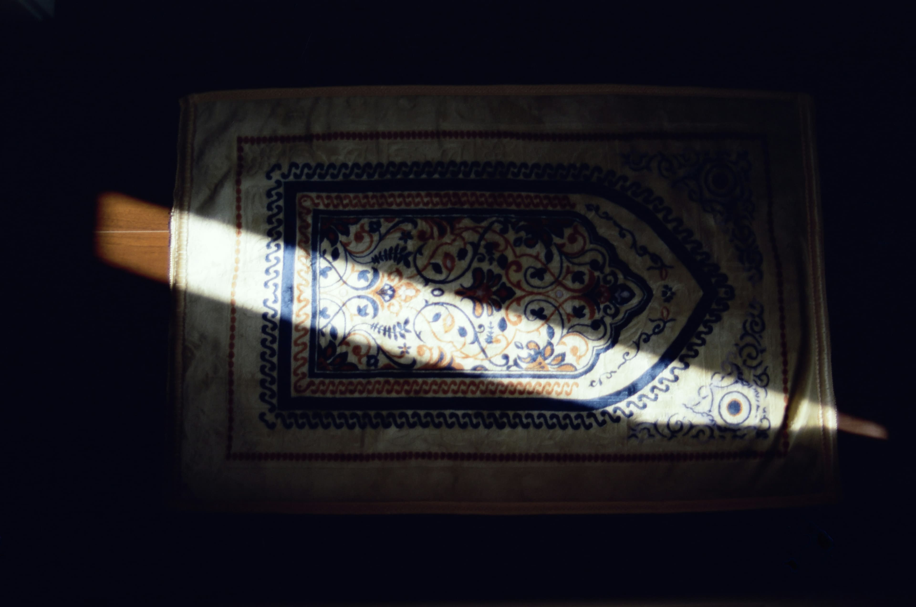 A prayer mat lit by a beam of light